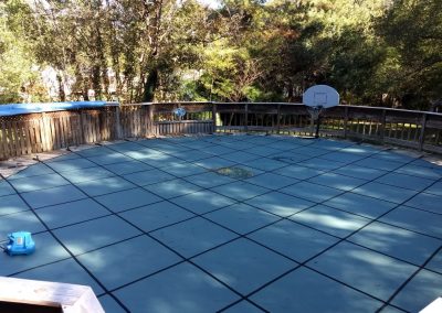 A green safety cover placed on top of an aboveground pool before winter.