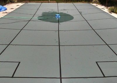 A big pool with a safety cover over it.