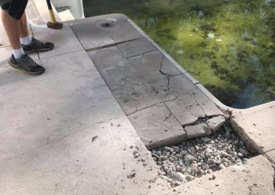 An employee smashing old concrete around an old pool.